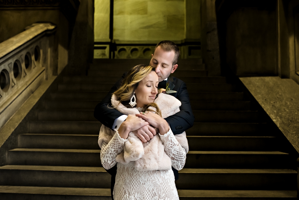 A groom holds his bride on the steps of city hall in Philadelphia.